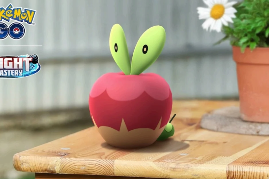 A digital creature resembling an apple sits on a wooden table near a plant pot. Logos for "Pokémon GO" and "Mighty Mastery" are visible.
