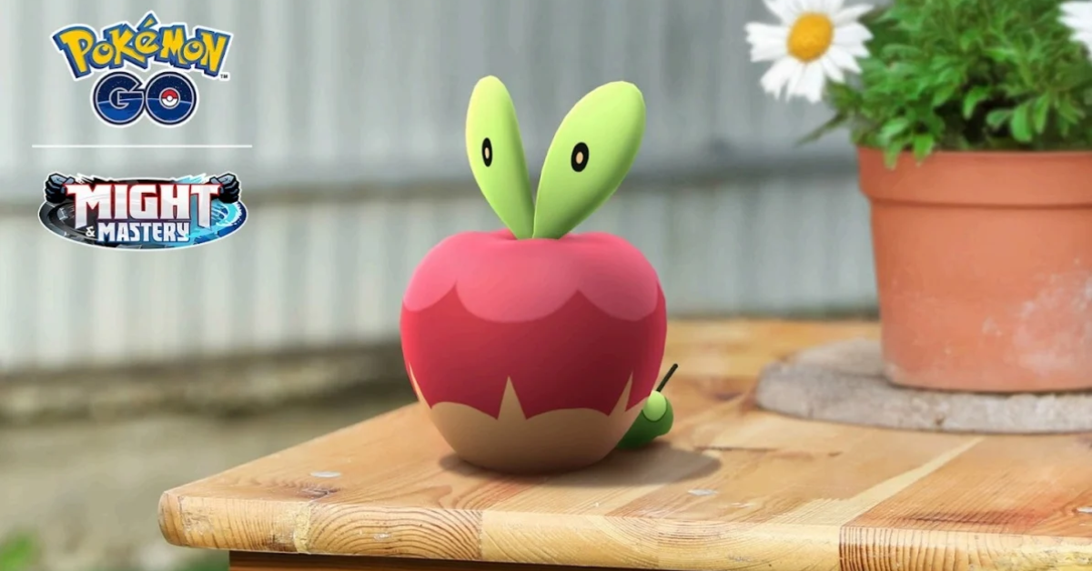 A digital creature resembling an apple sits on a wooden table near a plant pot. Logos for "Pokémon GO" and "Mighty Mastery" are visible.