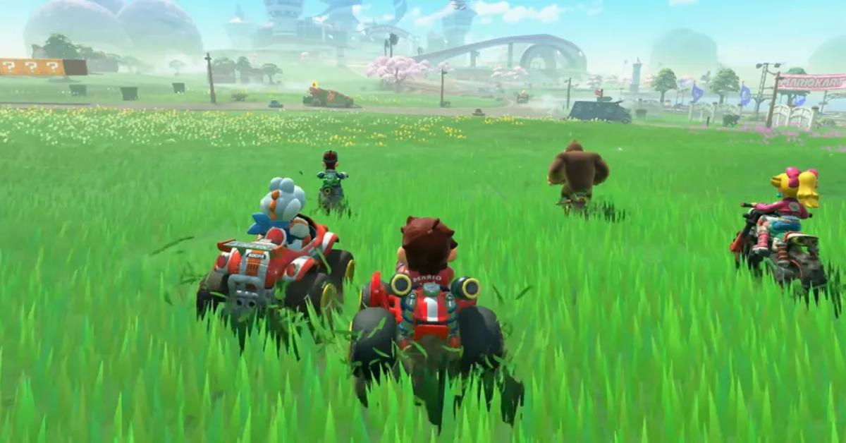 Mario, Donkey Kong, and other characters ride across a lush green field on ATVs and bikes in Mario Kart World, heading toward a futuristic city track in the distance.